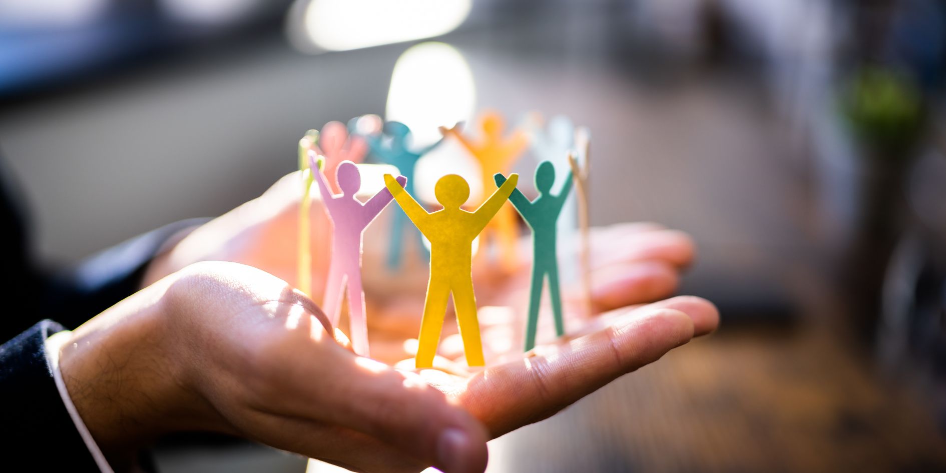 hands holding paper cut outs of people