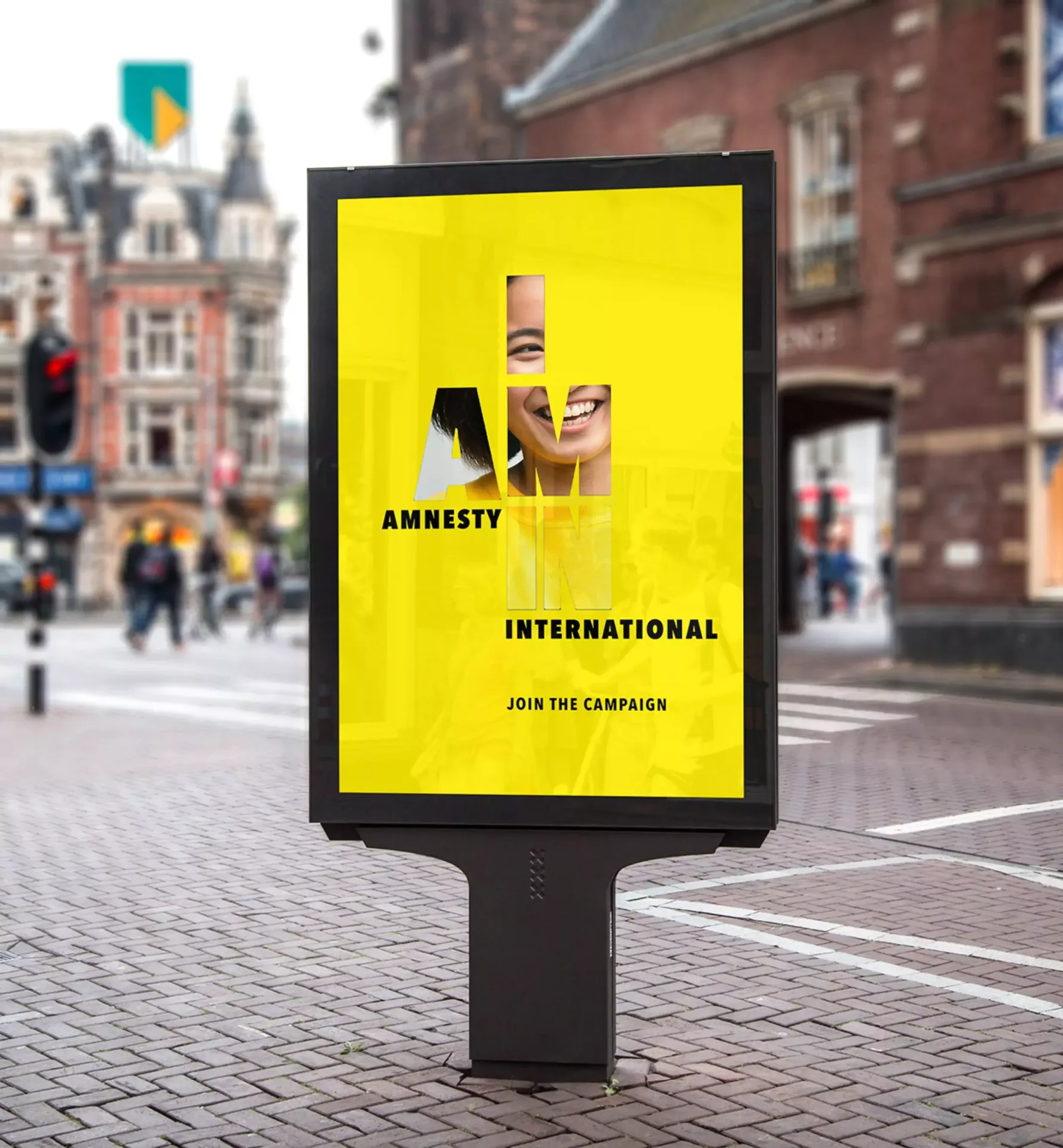 Yellow Amnesty International street billboard standing on an urban city sidewalk