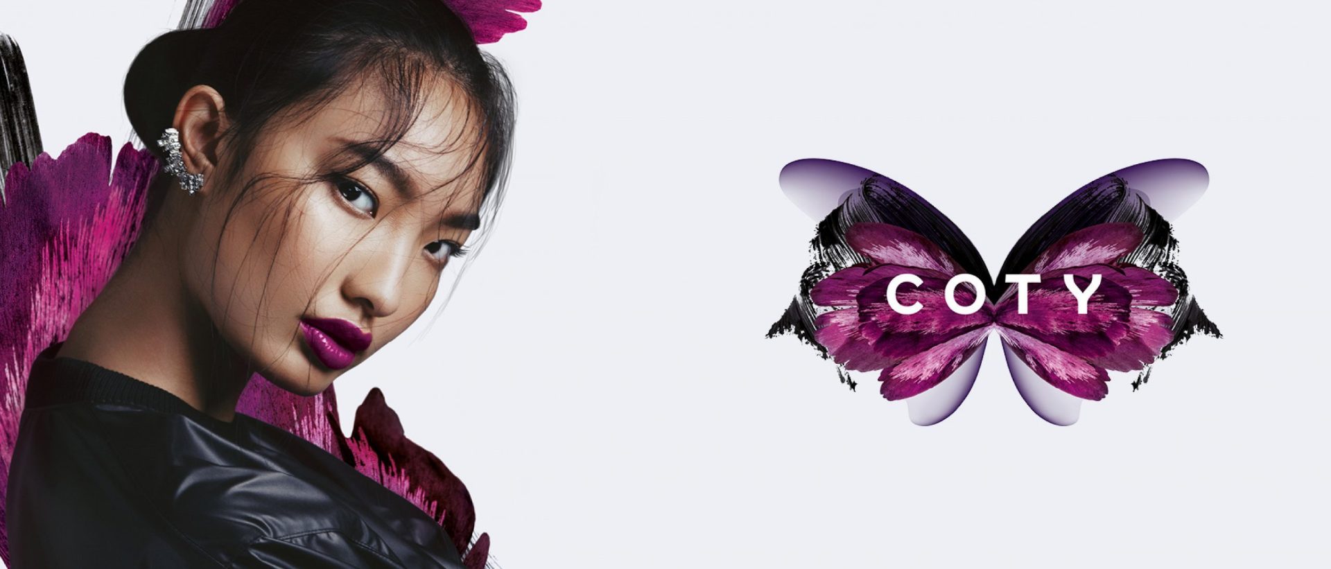 Asian female model with bold purple lipstick beside the COTY purple butterfly graphic artwork