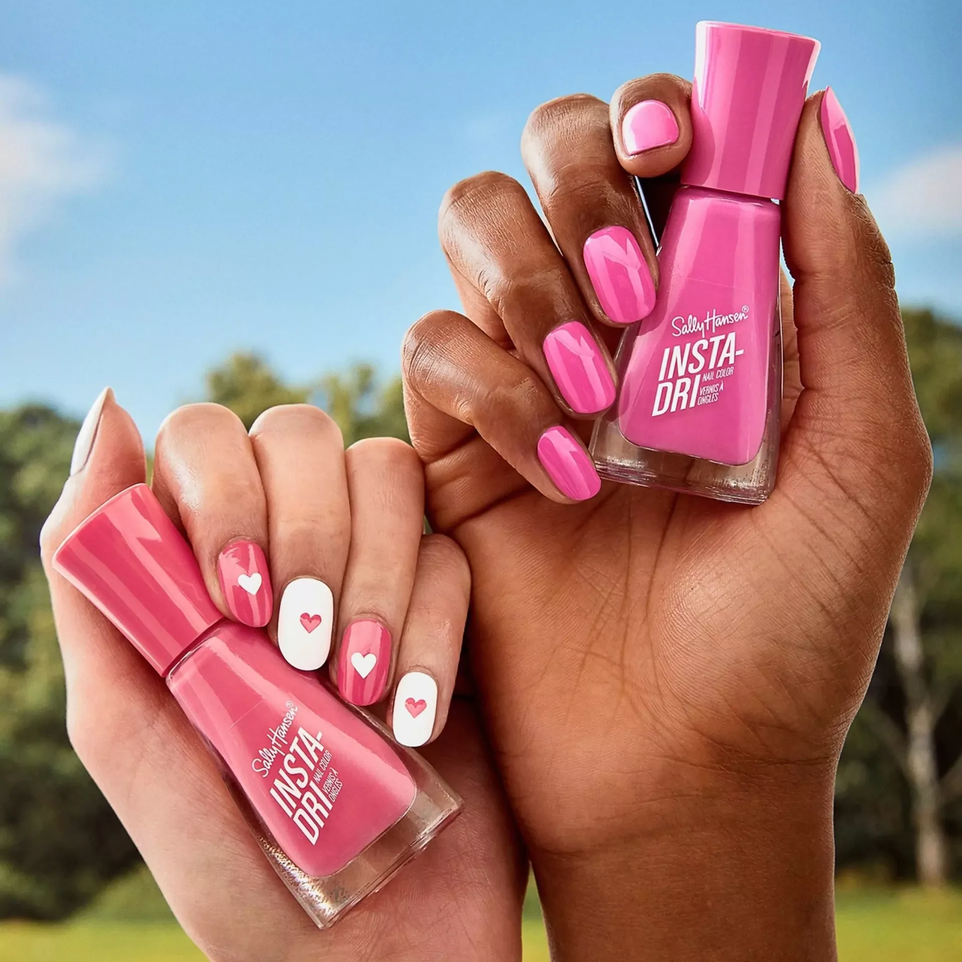 Close-up of manicured hands holding bright pink nail polish bottles