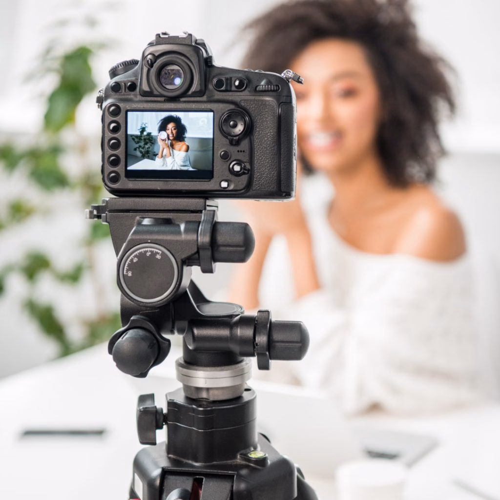 influencer Un appareil photo reflex numérique professionnel monté sur trépied, parfaitement mis au point, filmant une jeune femme souriante aux cheveux bouclés lors d'un tournage vidéo en studio ou d'une session de diffusion en direct.